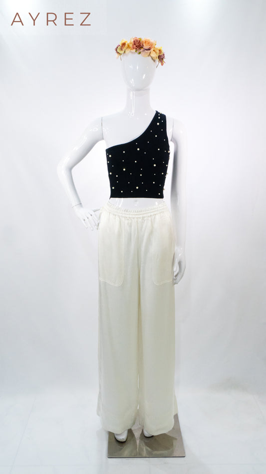 Top negro asimétrico con aplicaciones y pantalón de lino blanco