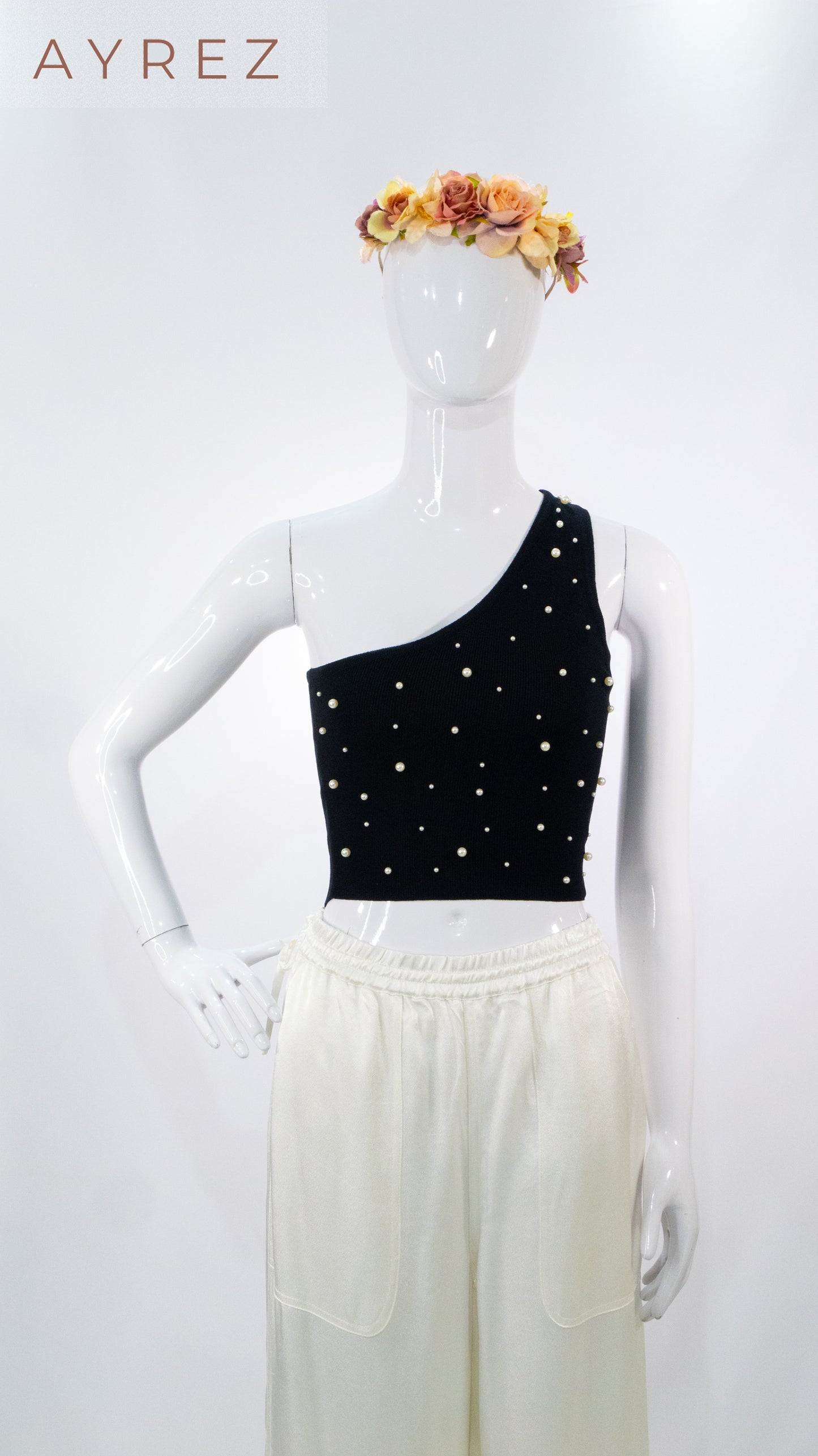 Top negro asimétrico con aplicaciones y pantalón de lino blanco